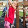 Kleines Mädchen klettert am Sherwood Spielgerät