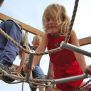 Kleines Mädchen klettert am Sherwood Spielgerät